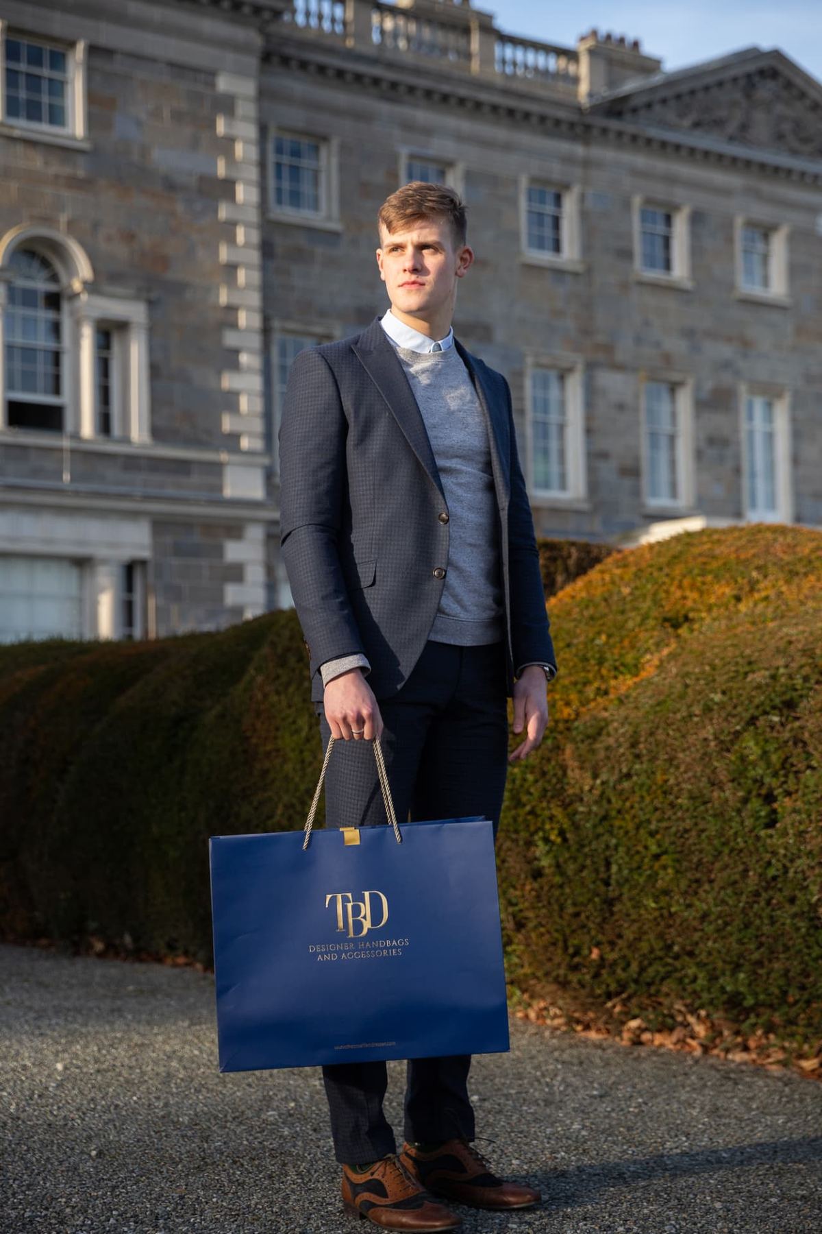 Large navy landscape carrier bag, matt laminated with gold foil logo, gold rope handles, and top reinforcement card.