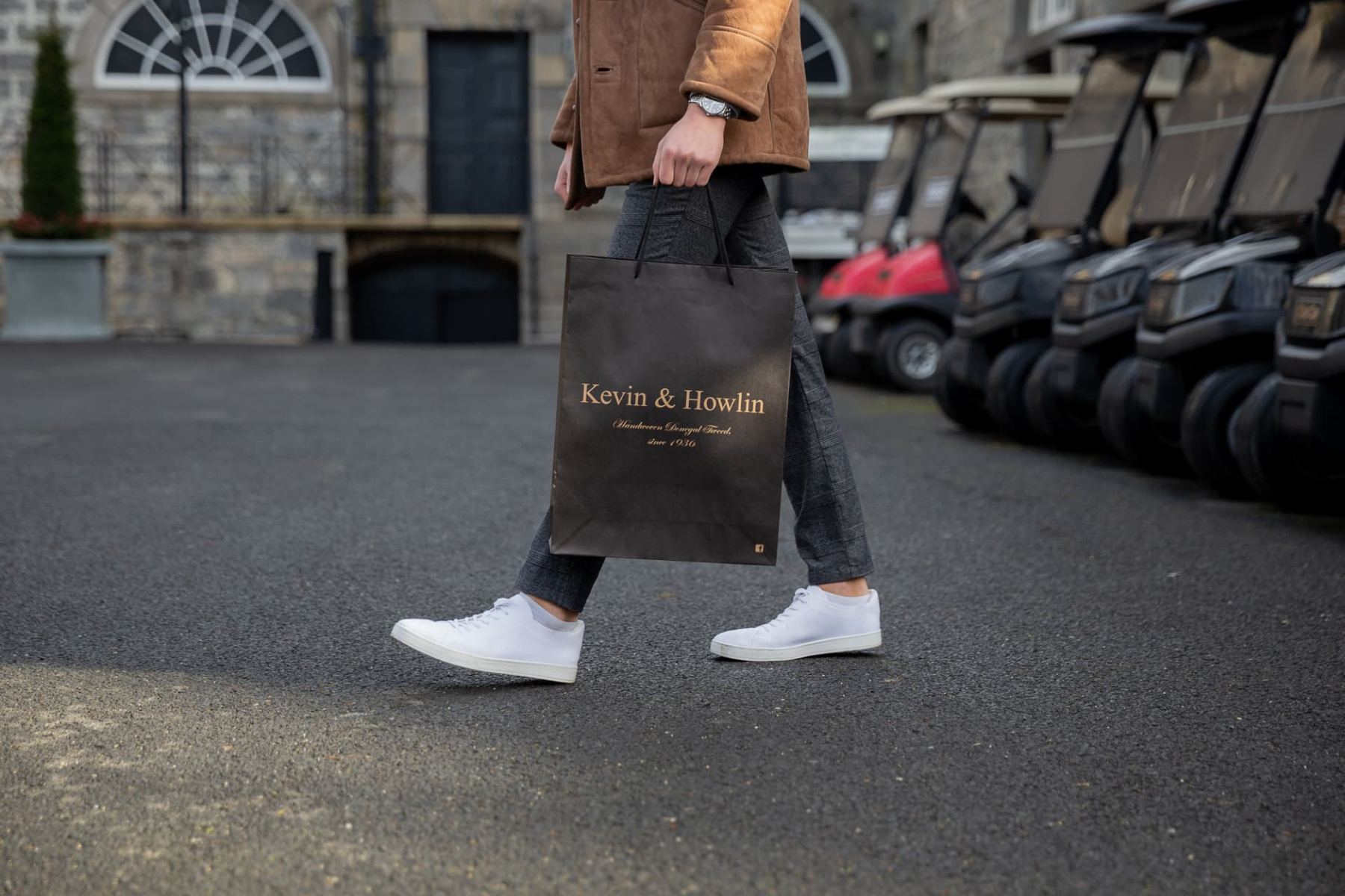 Black matt laminated paper carrier bag with gold foil logo, black rope handles, and eyelet reinforcement for Kevin & Howlin.