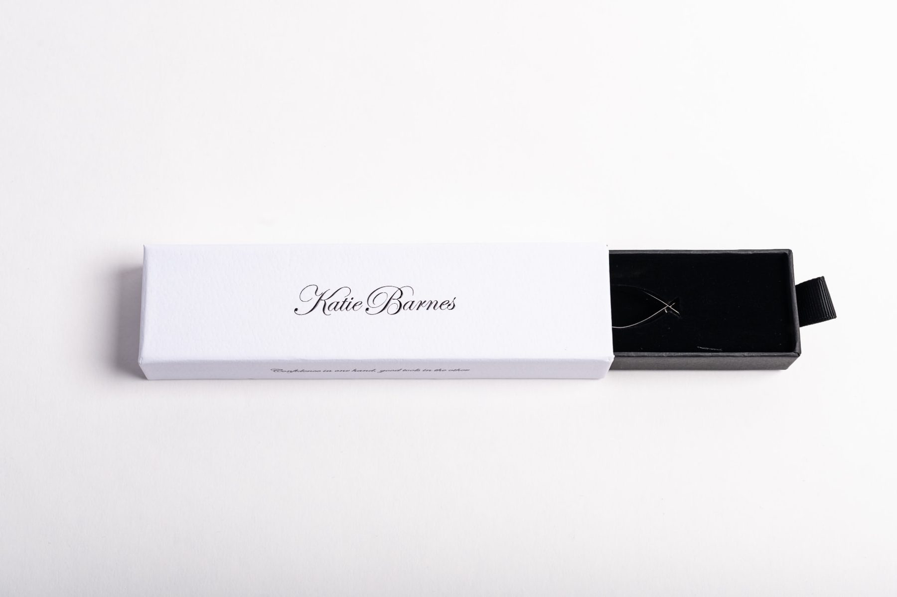 White rigid slide drawer gift box with black tray and black ribbon pull, featuring a black printed logo on the lid.