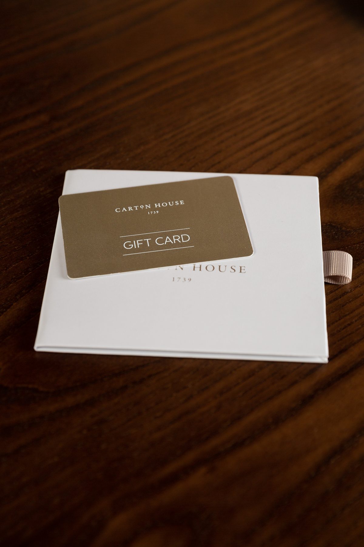 White rigid gift card wallet, Carton House logo, ribbon pull. Gold foil gift card: 'Carton House' and 'Gift Card'.