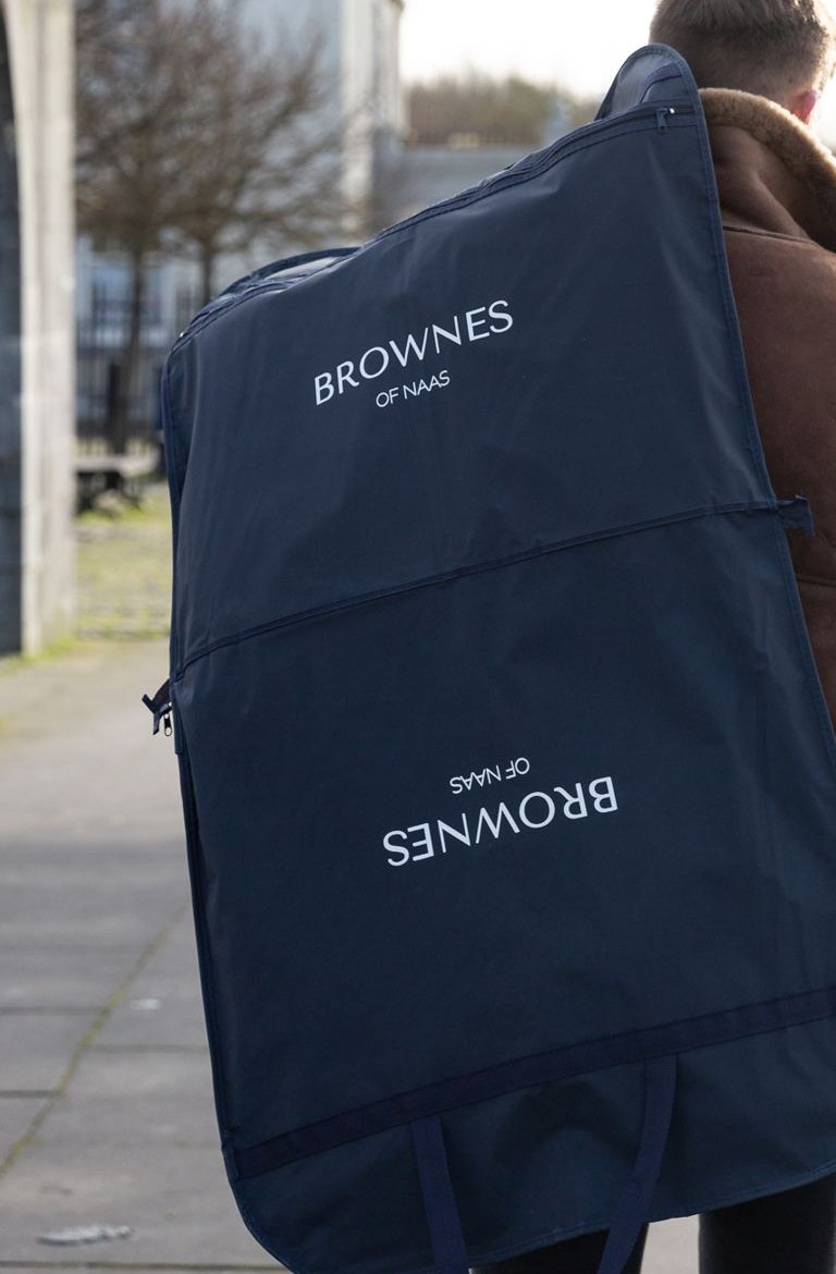 Navy garment cover bag with white 'Brownes of Naas' logo printing, featuring a top loop for hanging and base carry handles.
