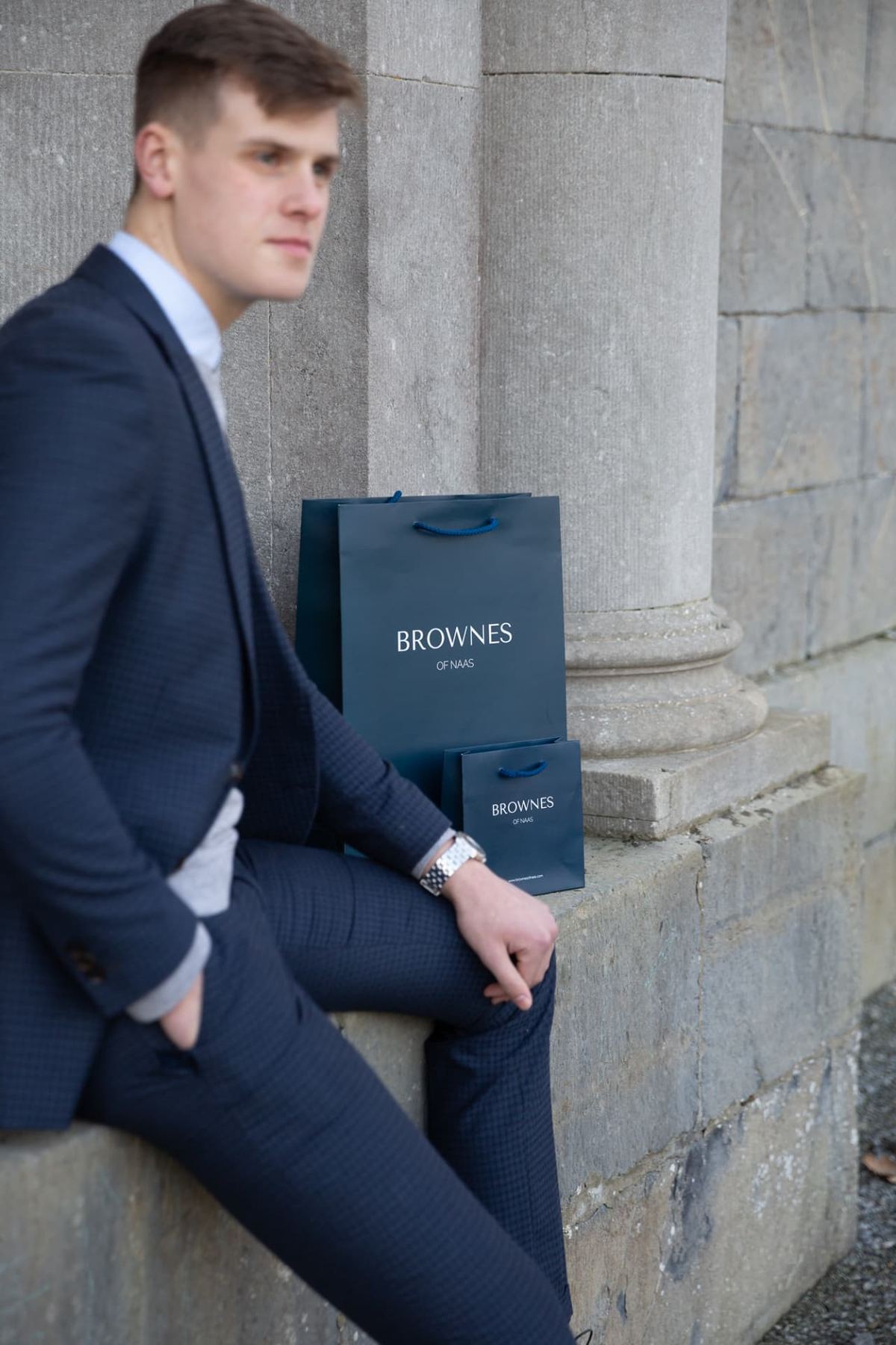 Two matt laminated navy rope handle bags with 'Brownes Of Naas' logo, one larger portrait format, one smaller portrait format.