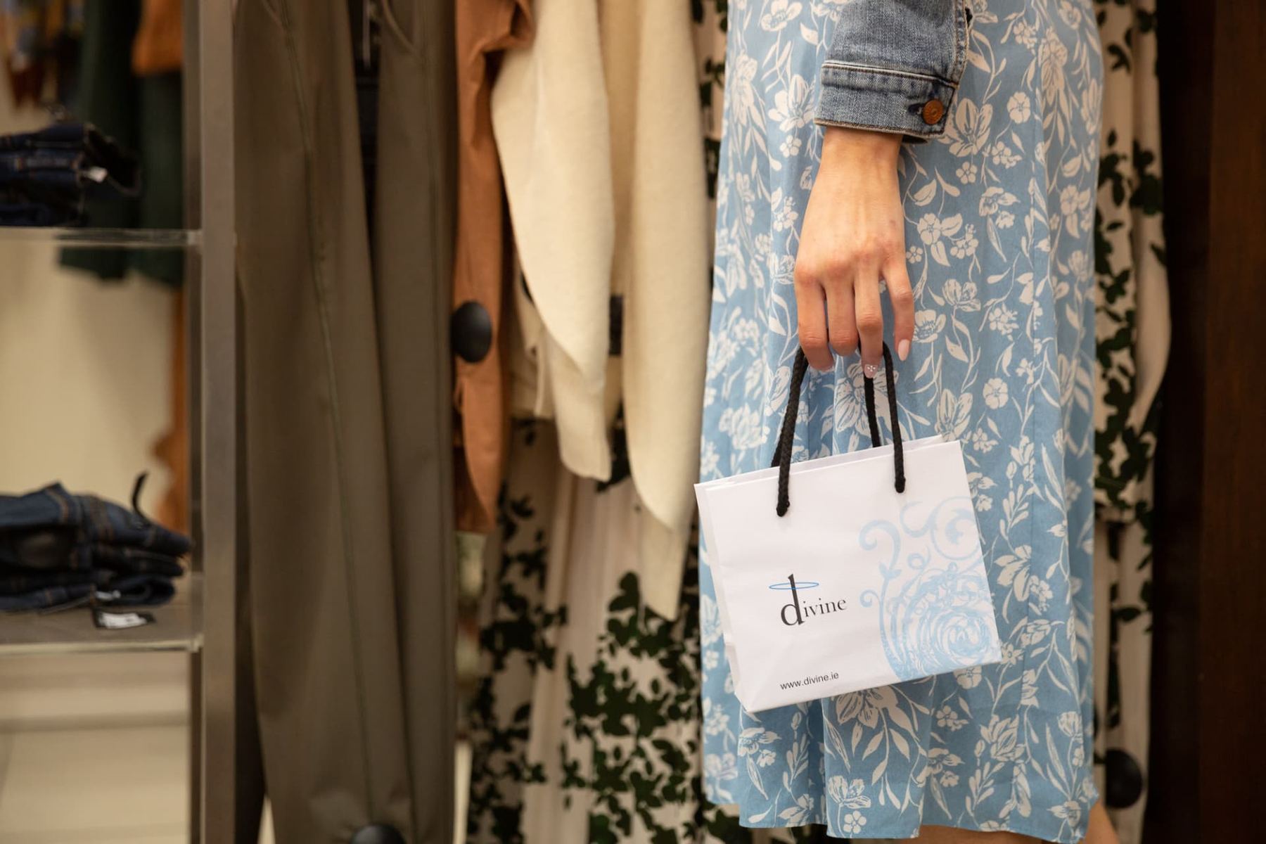 Small white paper carrier bag with a blue printed logo and design, featuring black twisted rope handles.