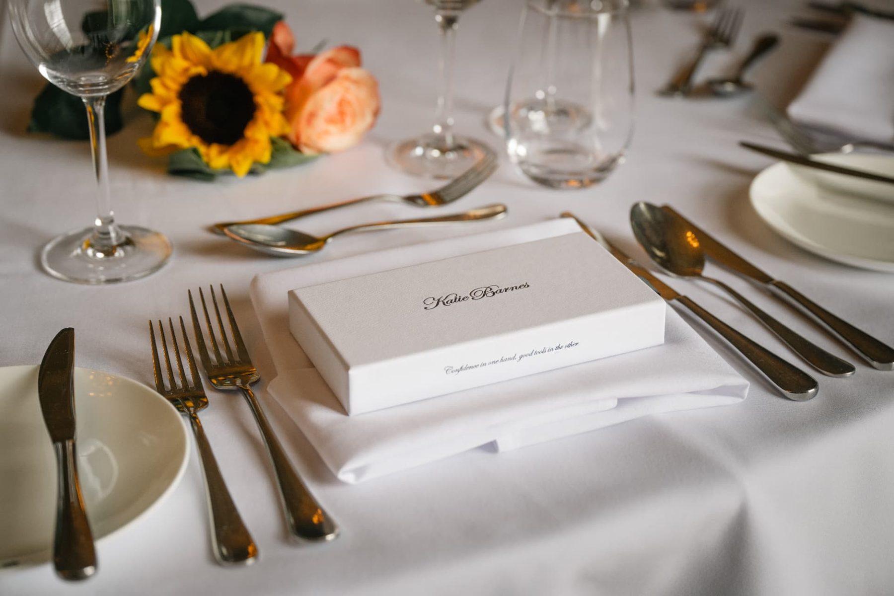 White rigid presentation box with a matte finish and black printed script logo and text, designed for gifting or retail.