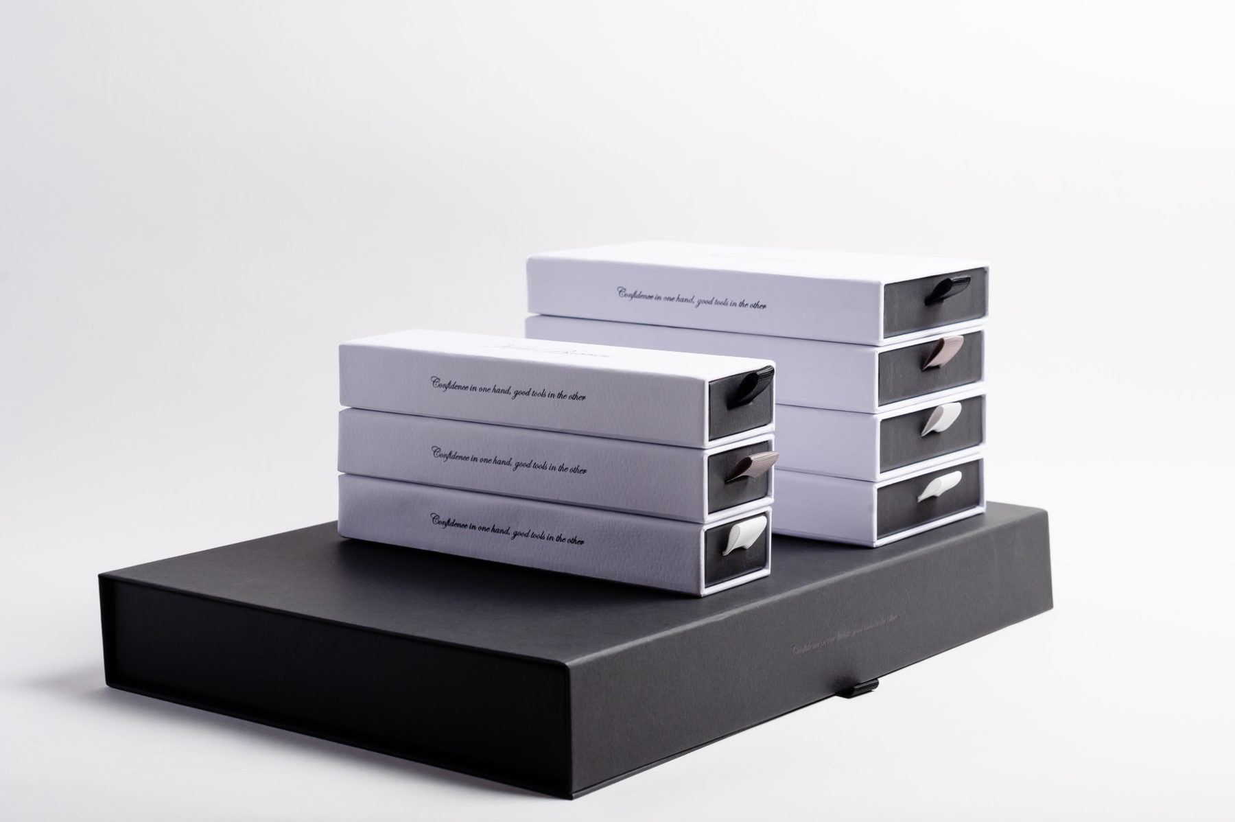White and black rigid slide drawer boxes, matt finish with black print and ribbon pulls, presented on a larger black rigid gift box.