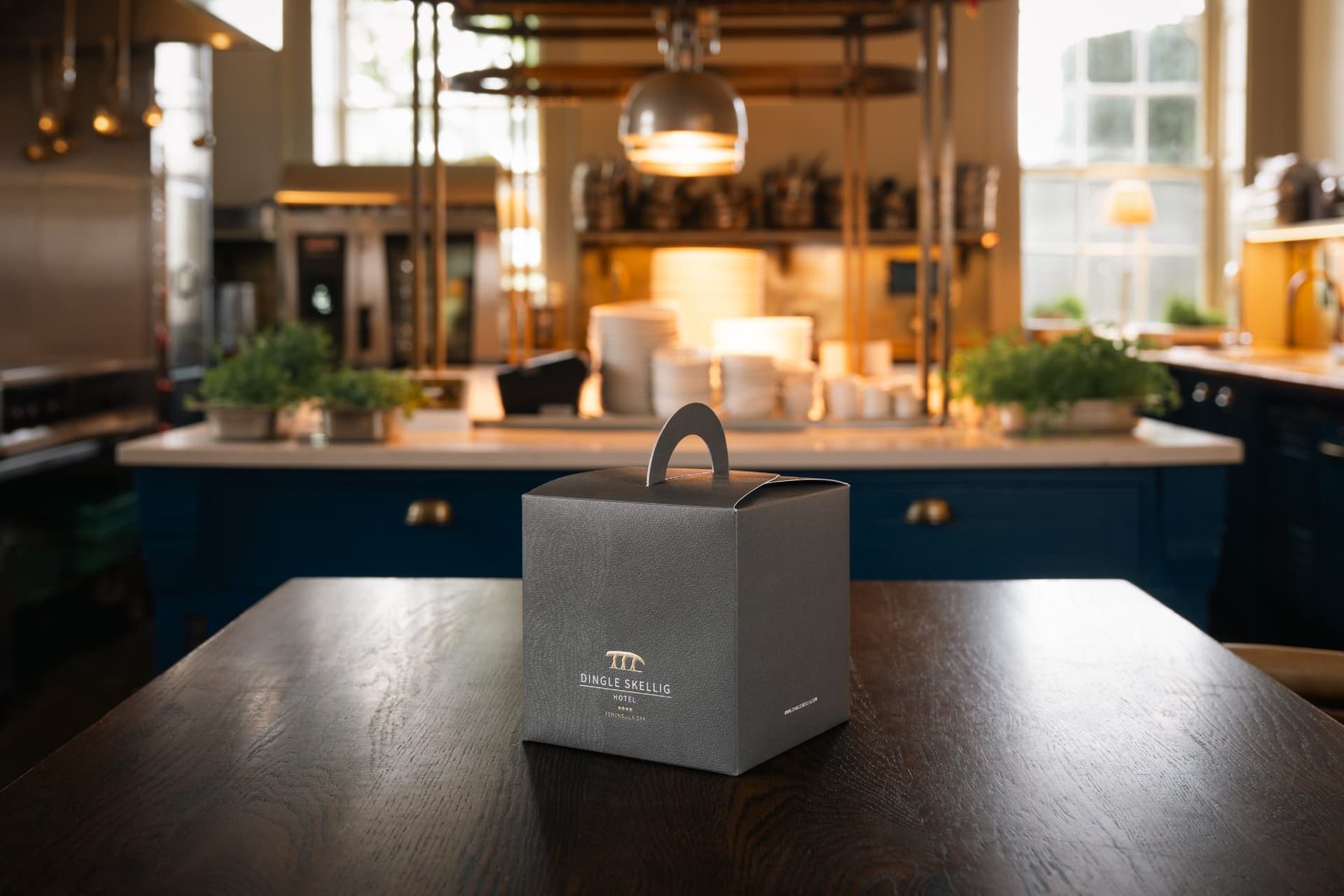 Matt grey cube box with integrated carry handle and gold foil logo. Single piece construction for takeaway use.