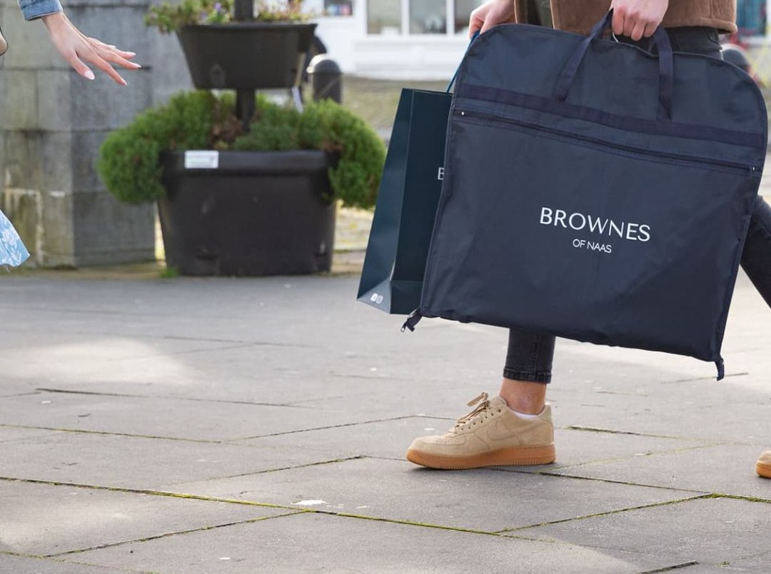 Navy garment carrier bag with black webbing handles and a prominent white printed logo on the front. Features a zip closure.