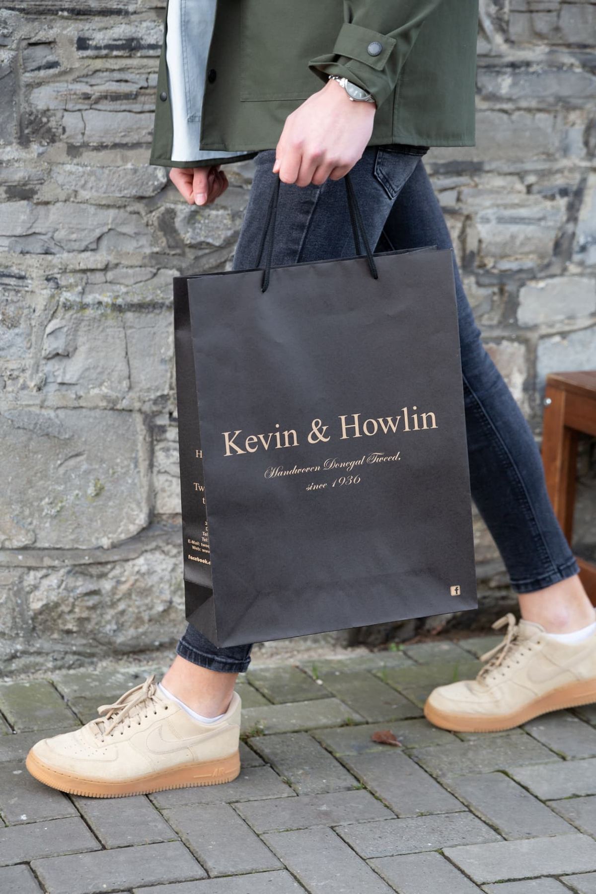 Black matt laminated paper carrier bag with gold printed logo and black twisted cord rope handles. Retail shopper bag format.